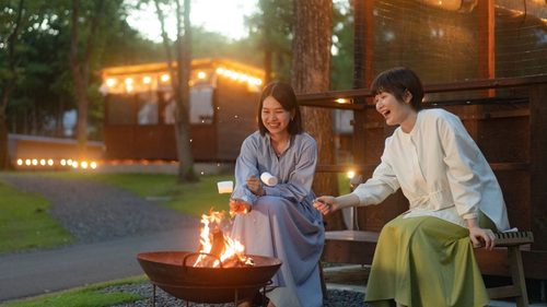 WHITE LAMPの客室デッキにあるプライベートテラスで友人と焚き火体験を楽しむ様子